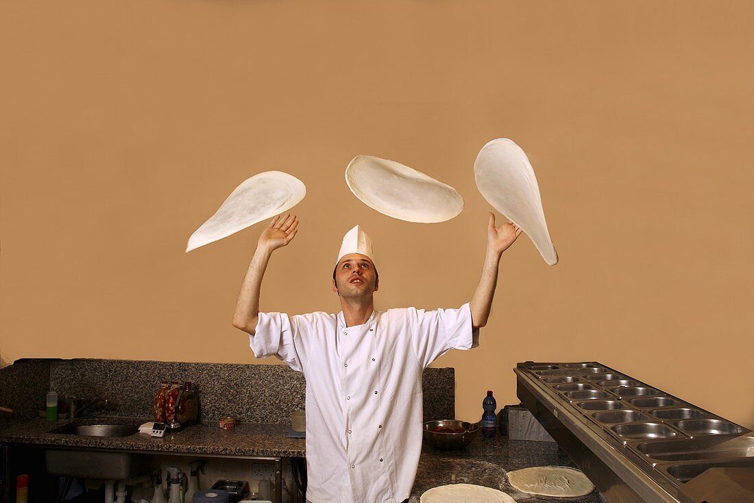 Italian pizza baker throwing dough into the air