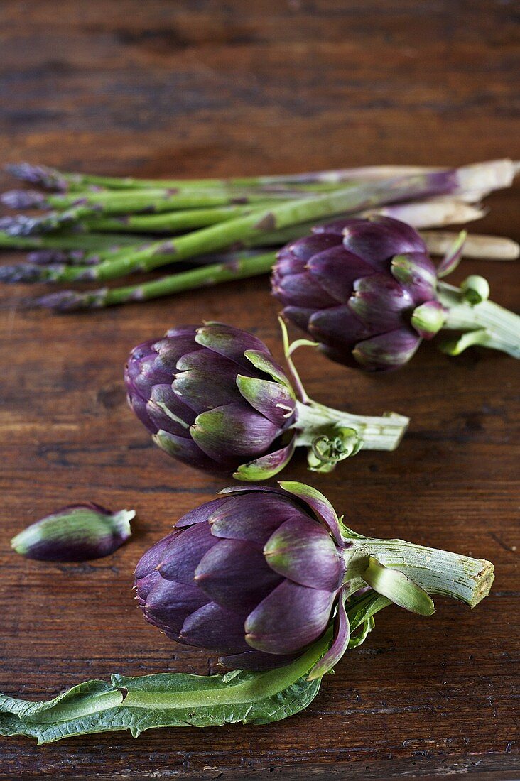 Artichokes and green asparagus on wooden background