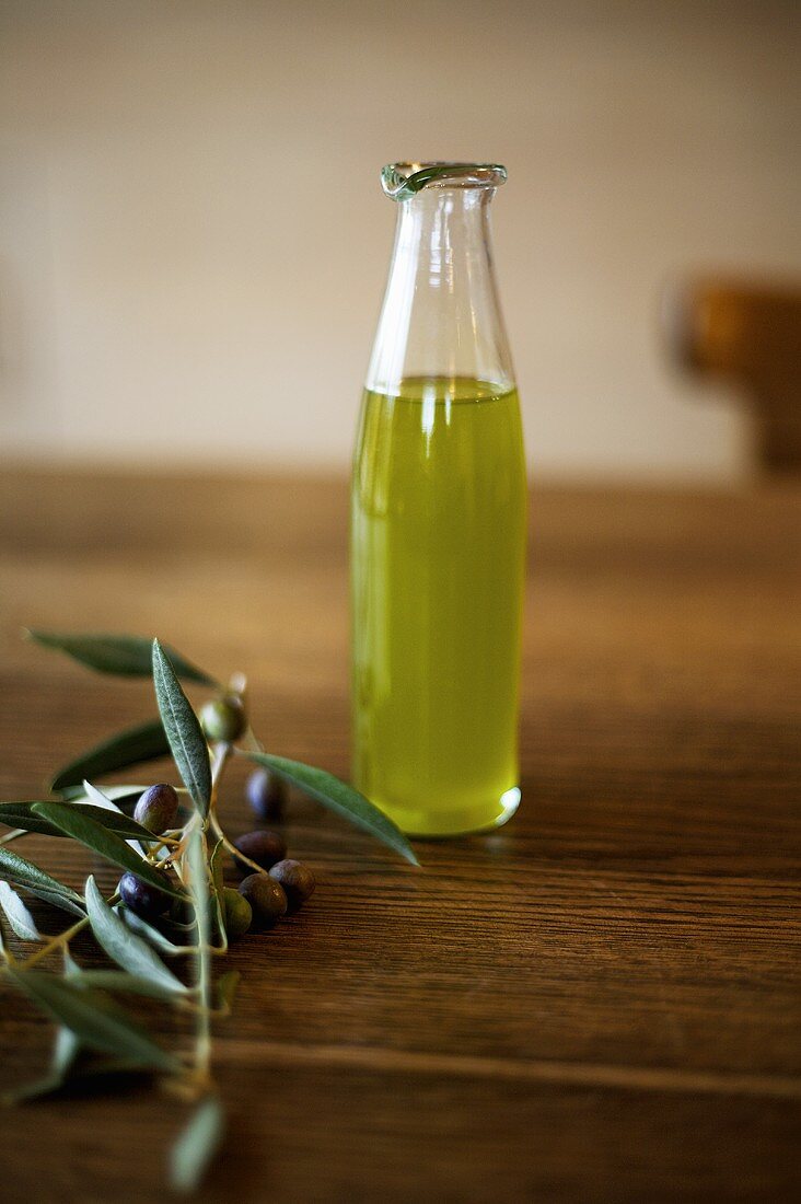 A small bottle of olive oil and an olive sprig