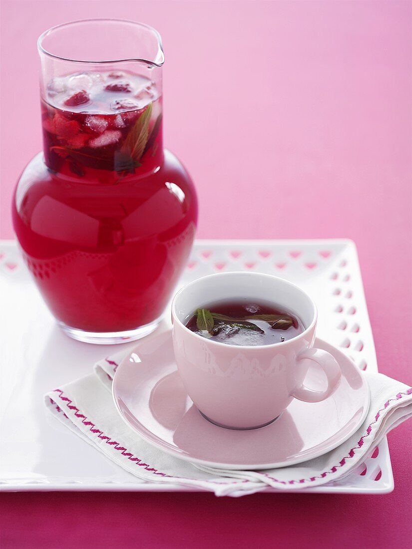 Cold berry tea with mint in jug and cup