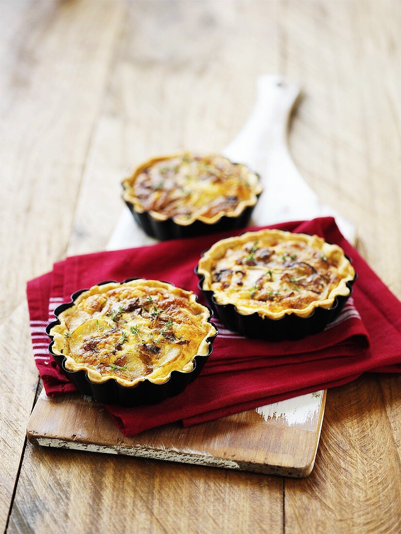 Kartoffel-Zwiebel-Tarteletts auf Schneidebrett