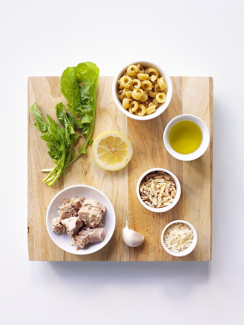 Ingredients for pasta and tuna dish on chopping board (overhead view)