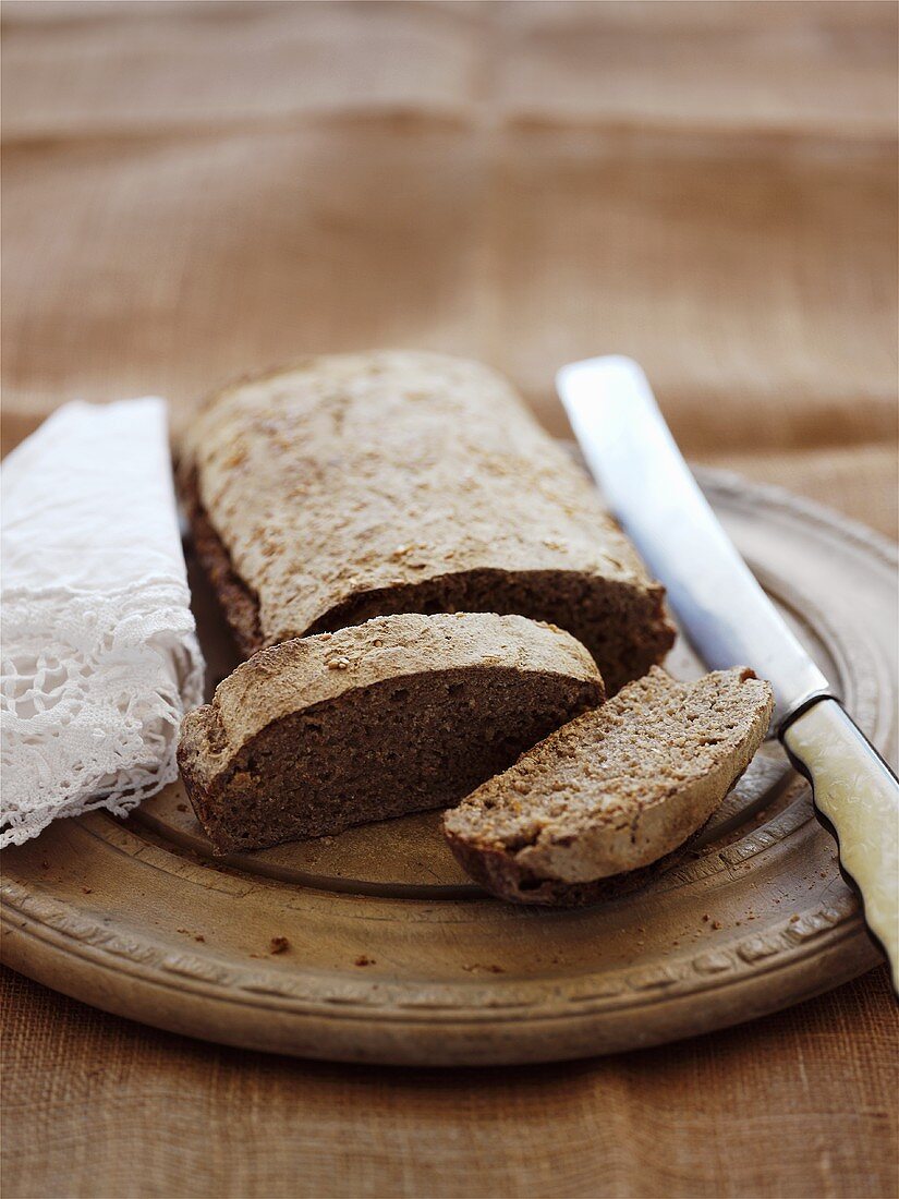 Partly-sliced loaf of bread on breadboard