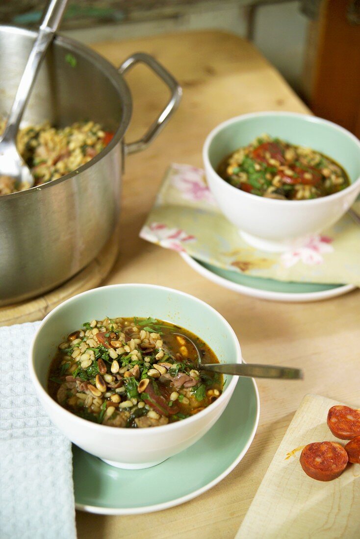 Barley soup with spinach, sausage and ham