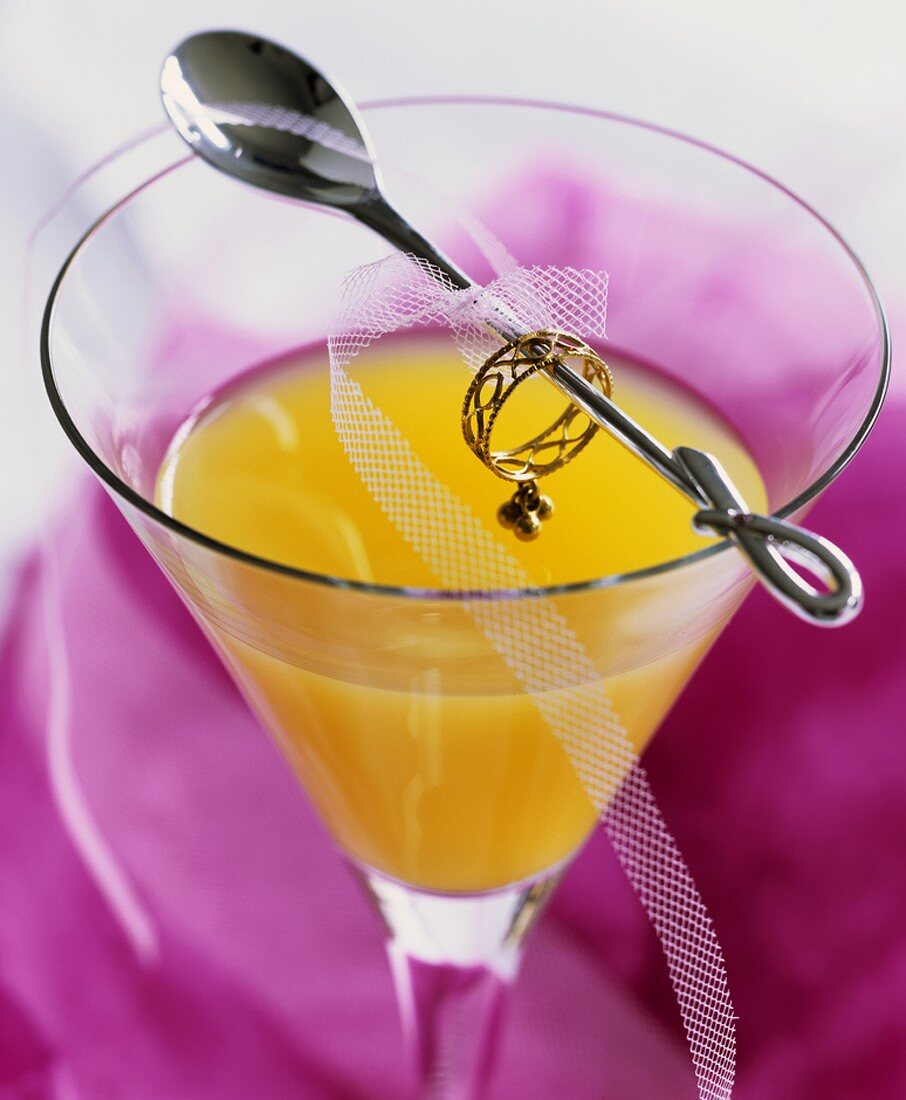 Drink made with orange juice, cocktail spoon with ring & net ribbon