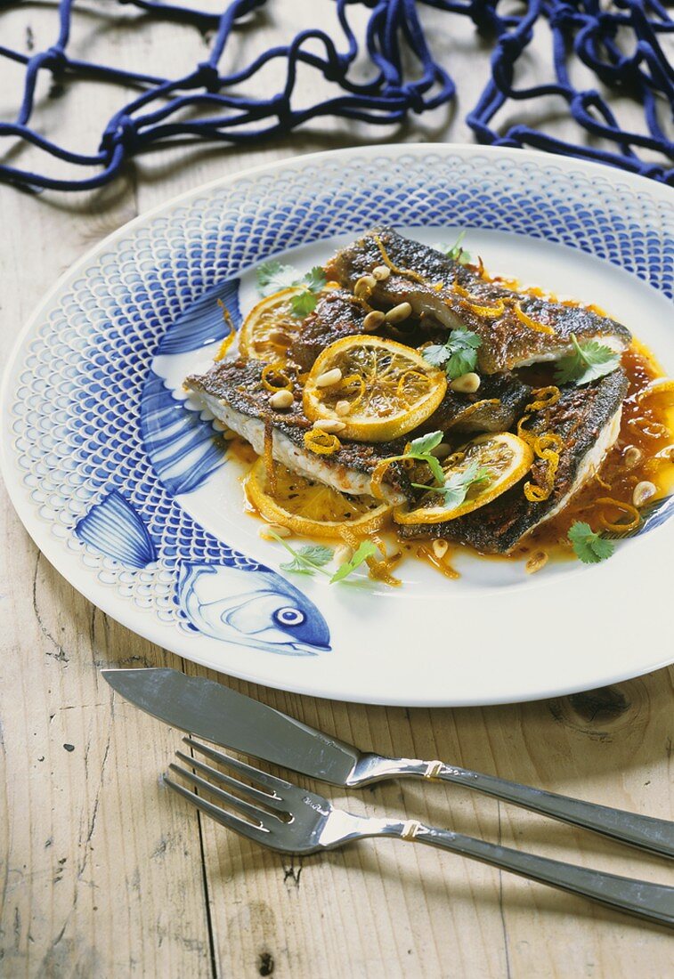 Fried fish with orange slices and pine nuts