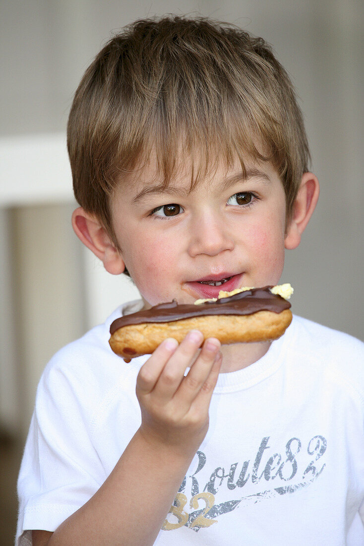 Boy eating a chocolate éclair