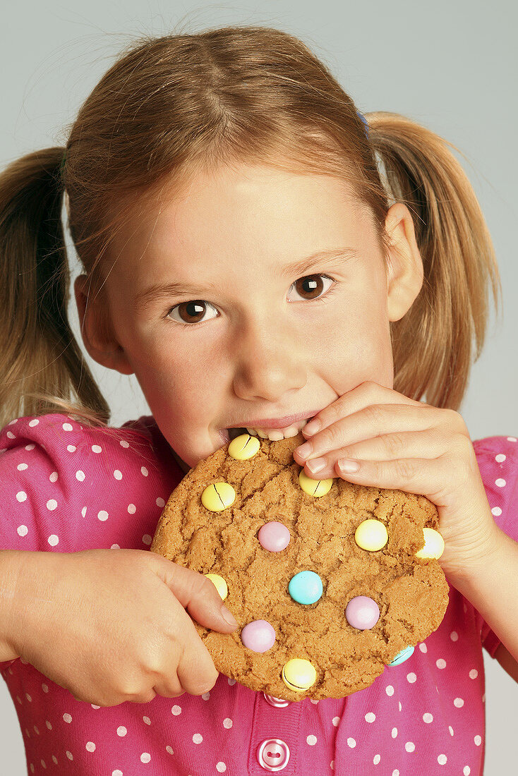 Girl eating a giant biscuit decorated with chocolate beans