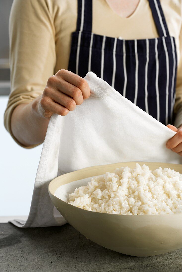 Covering cooked rice with a cloth