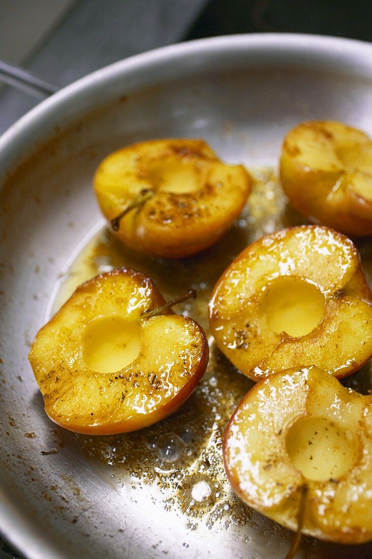 Frying apple halves in a frying pan