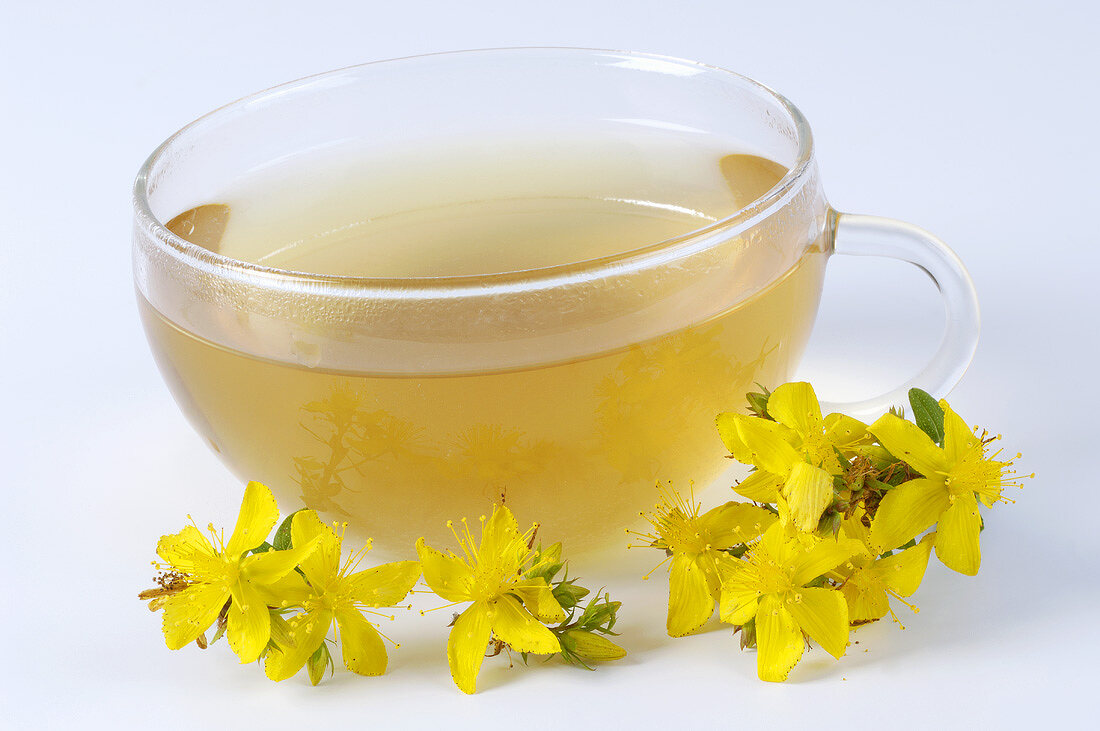 A cup of St. John's wort tea and St. Johns' wort flowers