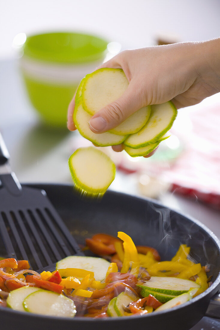 Putting courgette slices into a frying pan