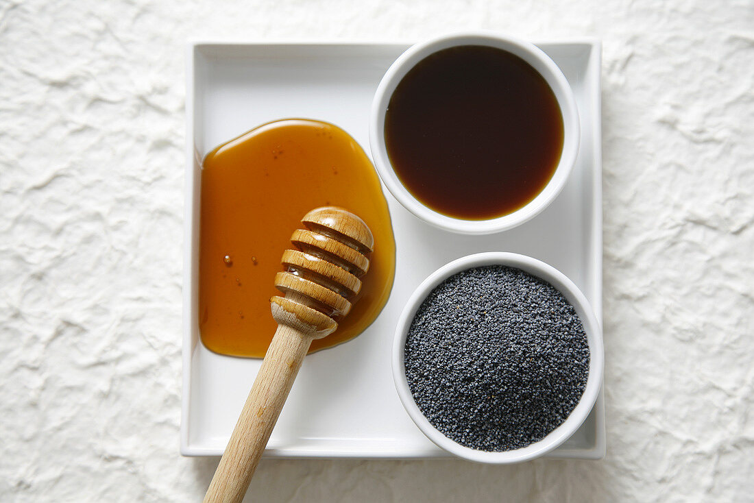 Honey with honey dipper and poppy seeds