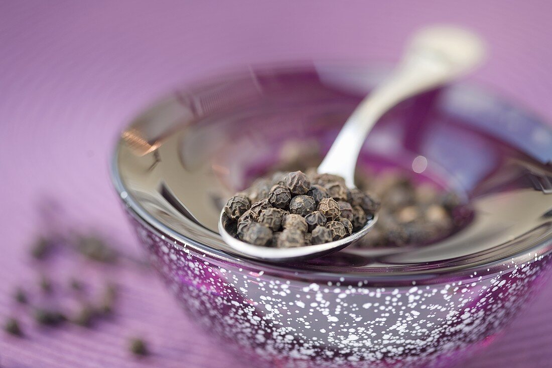 Black peppercorns on spoon