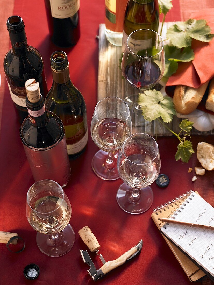 Weinflaschen, Weingläsern und Notizblock bei einer Weinprobe