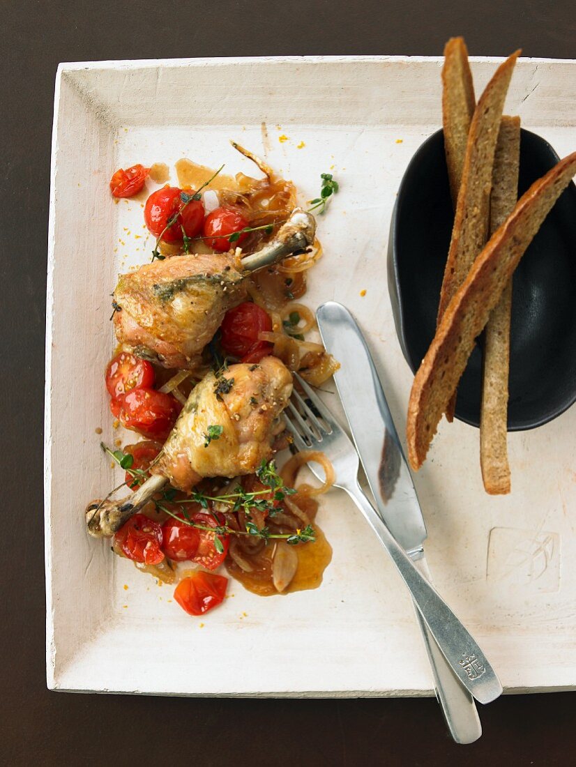 Gebratene Hähnchenkeulen mit Kirschtomaten und Brotstreifen