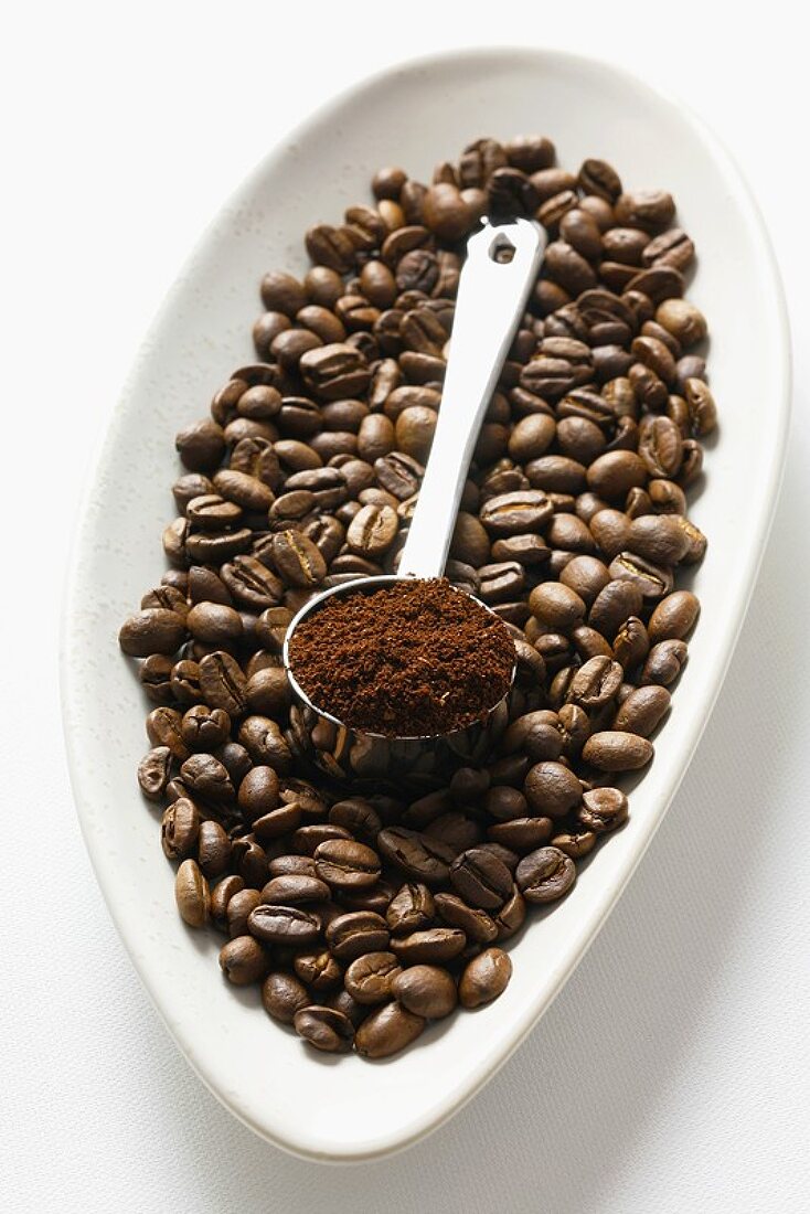 Kaffeebohnen und Messlöffel mit gemahlenem Kaffee