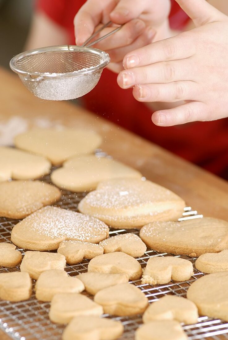 Dusting heart-shaped biscuits with icing sugar