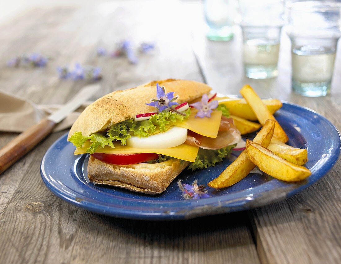 Ham and cheese sandwich with borage flowers and chips