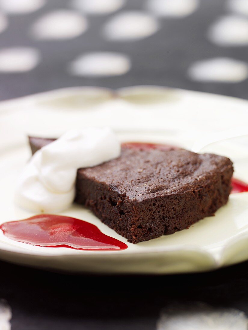 A piece of chocolate cake with cream and raspberry sauce