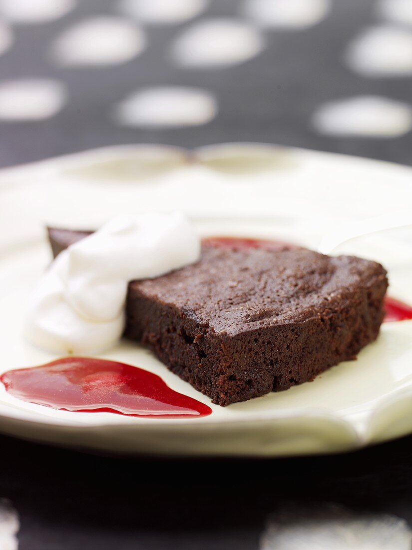 Ein Stück Schokoladenkuchen mit Sahne und Himbeersauce