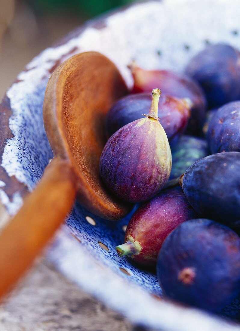 Fresh figs and wooden spoon in a colander