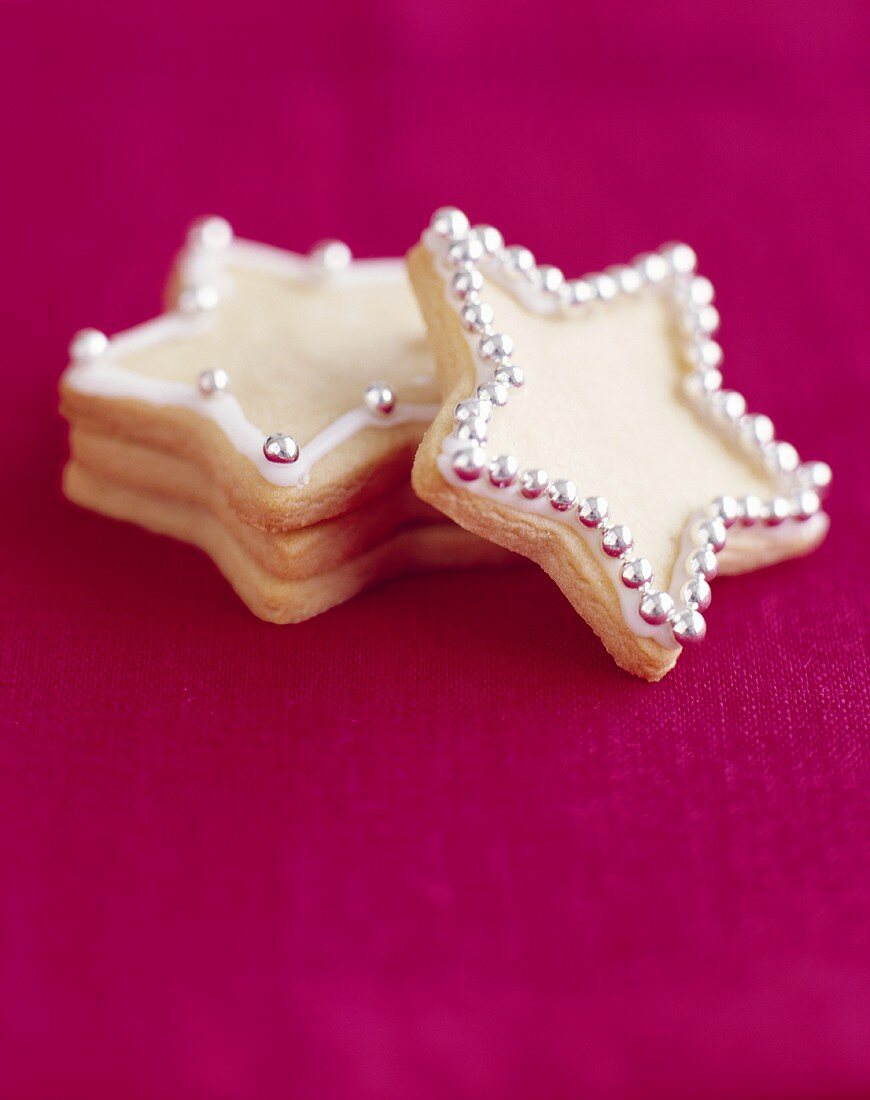 Star-shaped biscuits with dragées against purple background