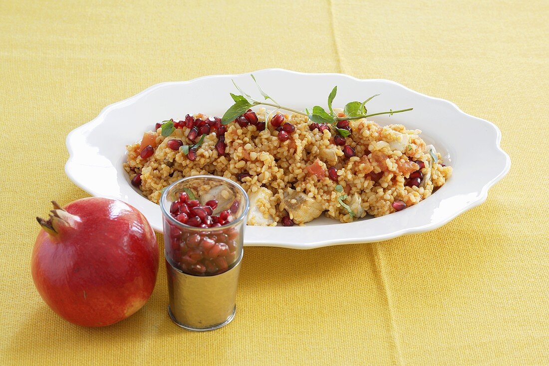 Bulgur with fish, pomegranate seeds and tomato