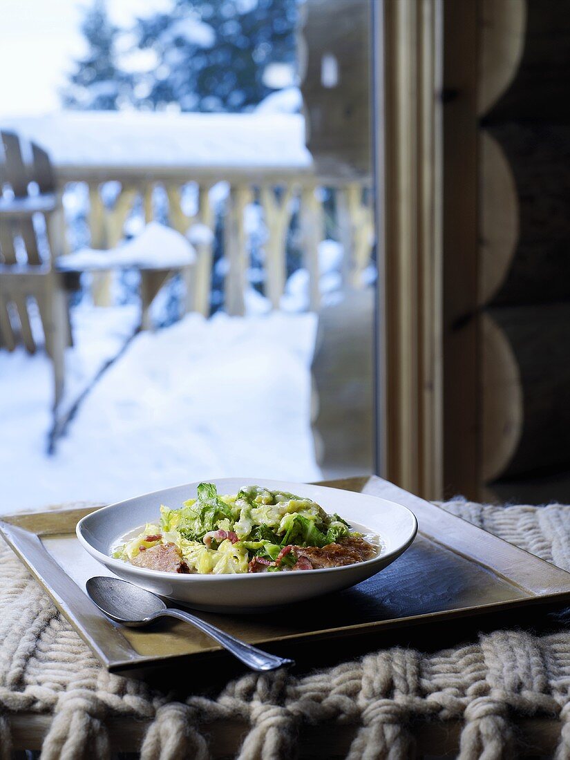 Cabbage and bacon dish, snow-covered garden in background