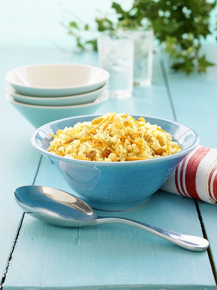 Couscous mit Rosinen und Karottenstreifen in blauer Schale