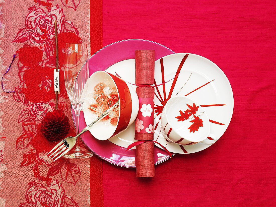 Place-setting with sparkling wine glass on pink background