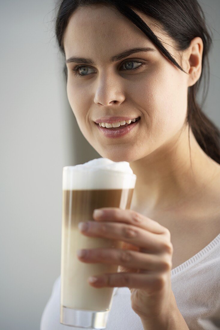 Junge Frau mit einem Glas Latte Macchiato