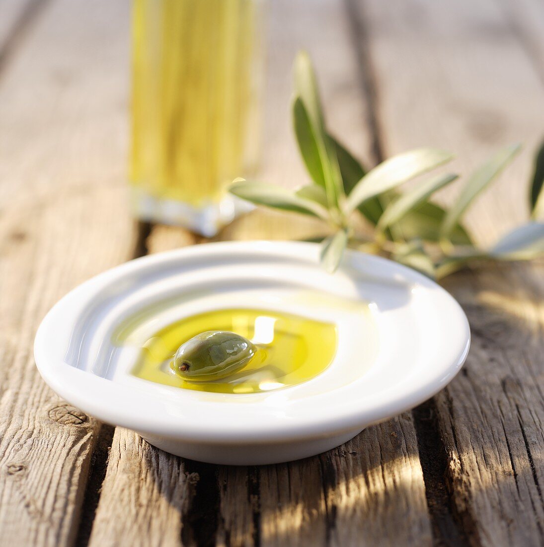 Schälchen mit Olivenöl und grüner Olive