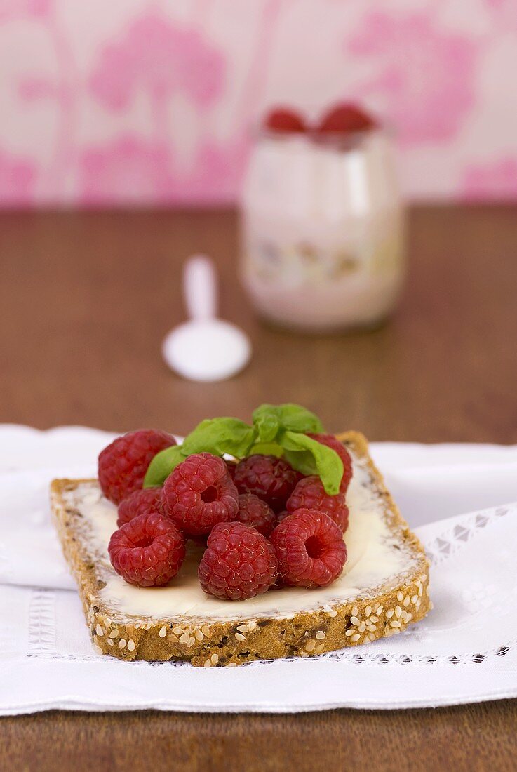 Fresh raspberries and basil on a slice of bread and butter