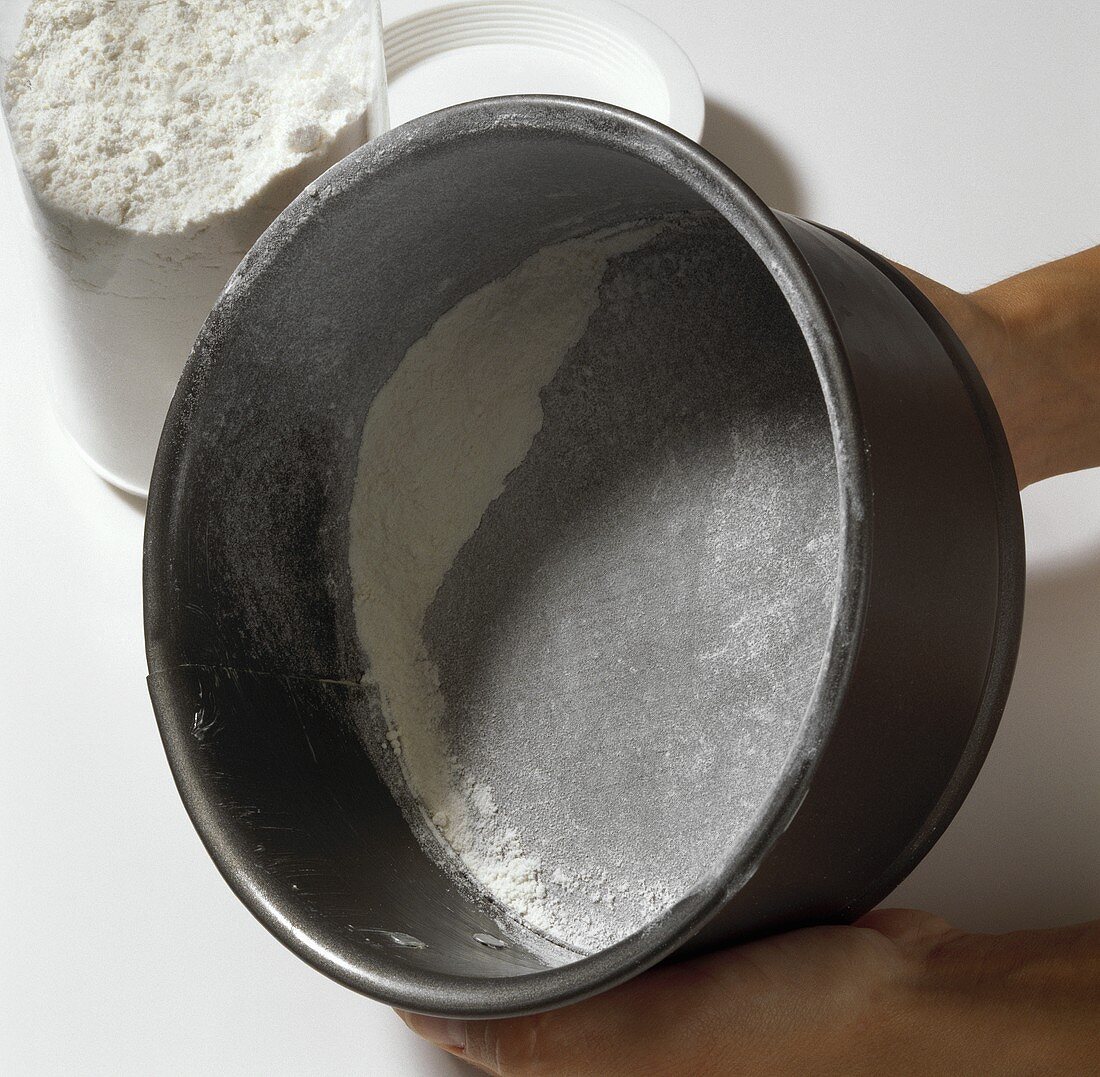Dusting a greased springform pan with flour