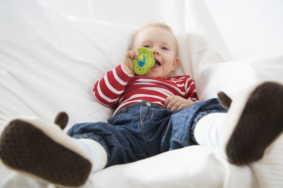 Kleines Kind sitzt mit Schnuller auf dem Sofa