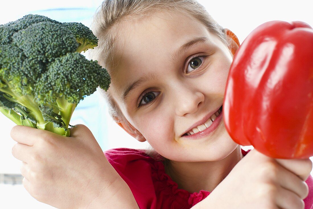 Mädchen hält Brokkoli und rote Paprikaschote