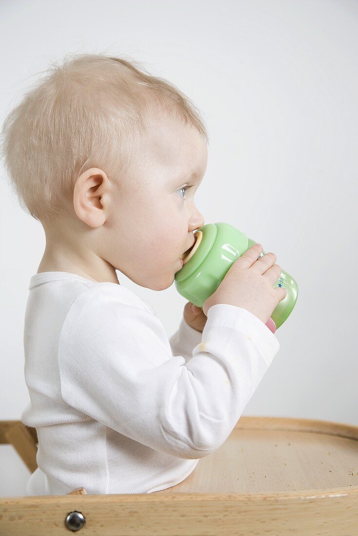 Small child drinking out of a training cup