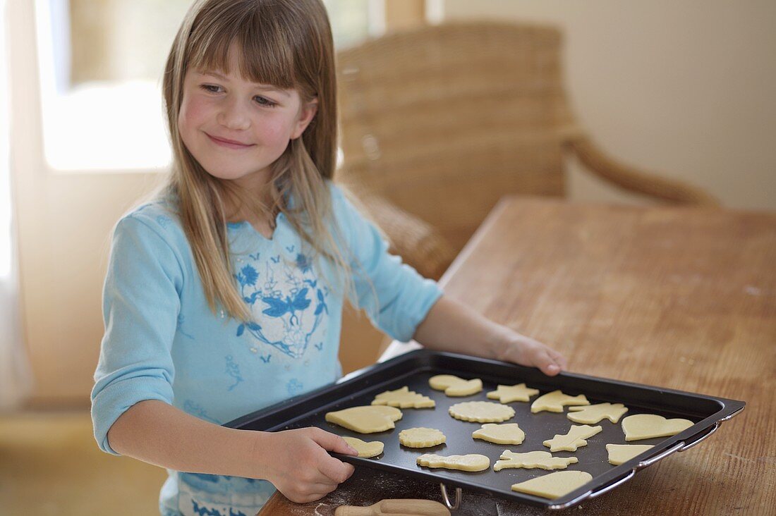 Girl holding a baking tray of biscuits