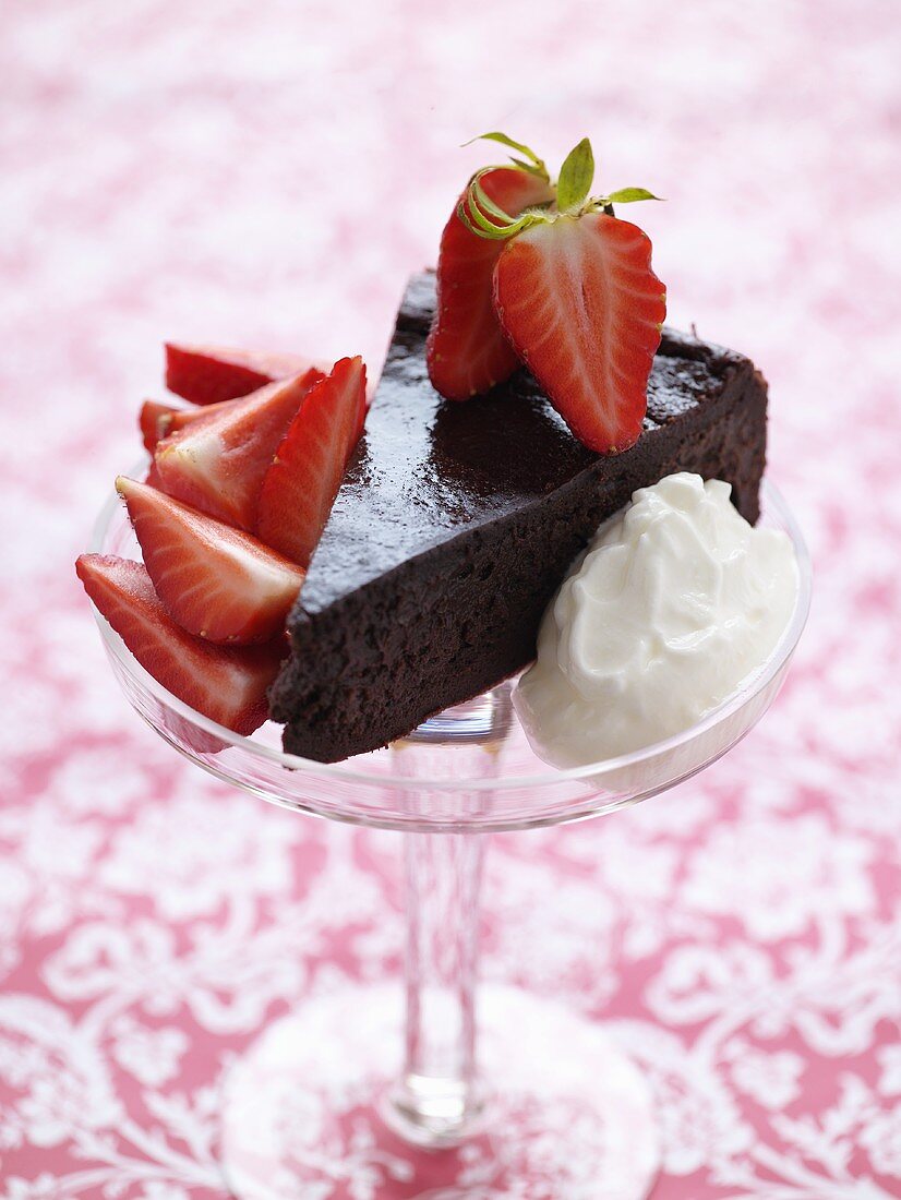A piece of chocolate cake with fresh strawberries & cream
