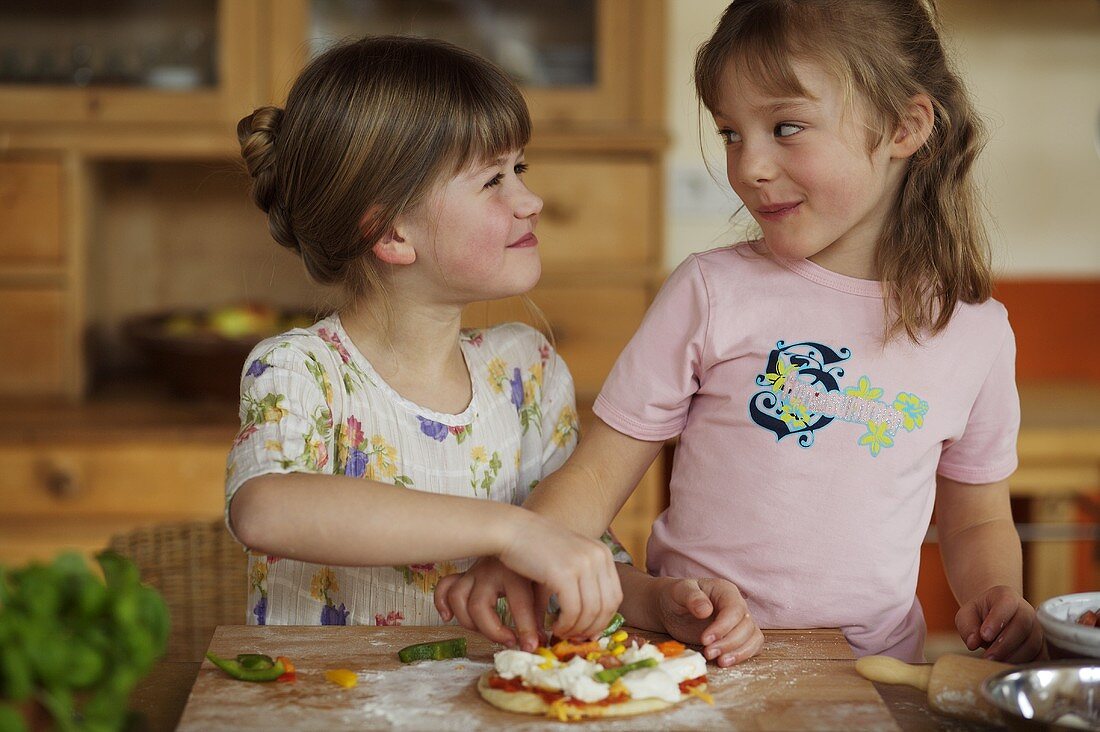 Zwei Mädchen belegen eine Minipizza