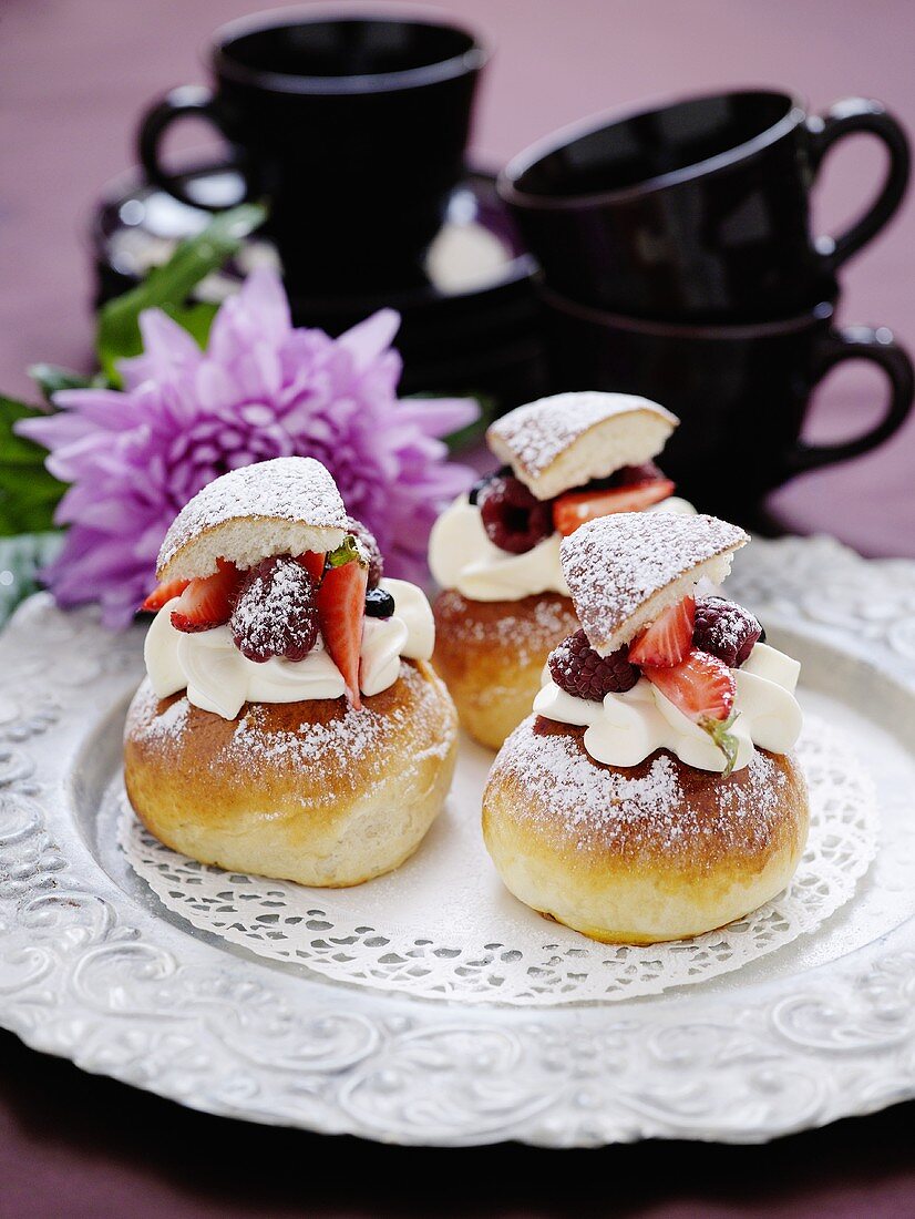 Cream buns with berries, coffee cups in background