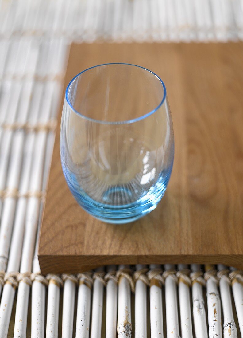 Blaues Wasserglas auf Holzbrett