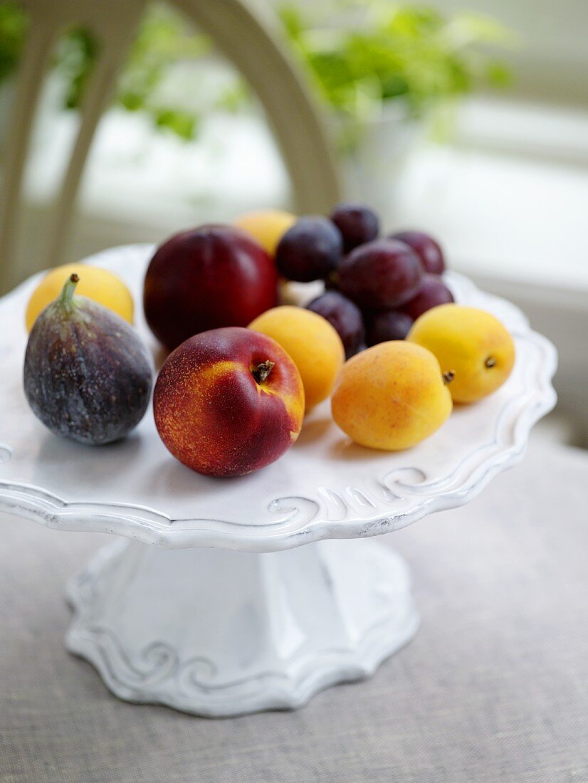 Nectarines, apricots, figs and grapes on cake stand