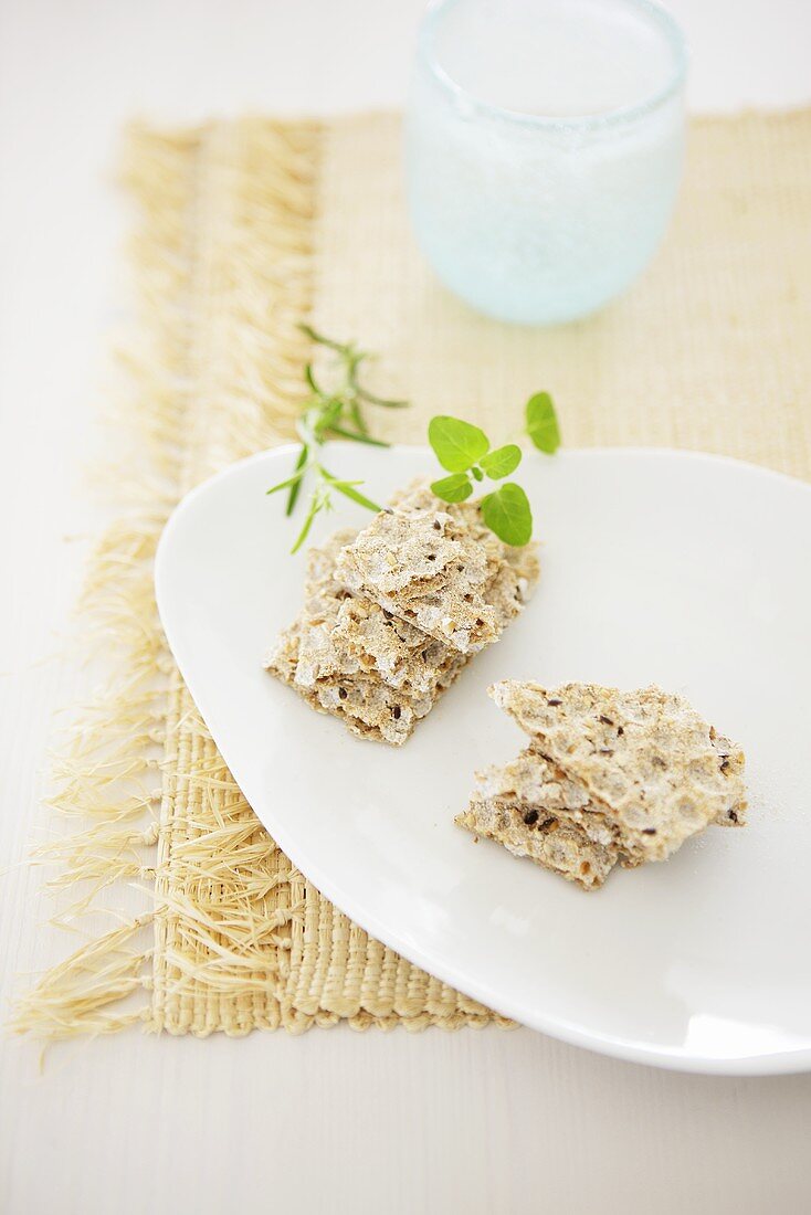 Wholemeal crispbread and herbs on white plate