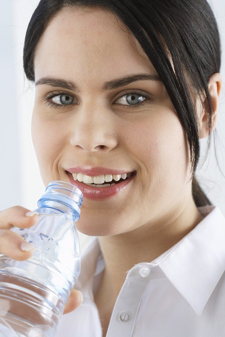 Junge Frau trinkt Mineralwasser aus der Flasche