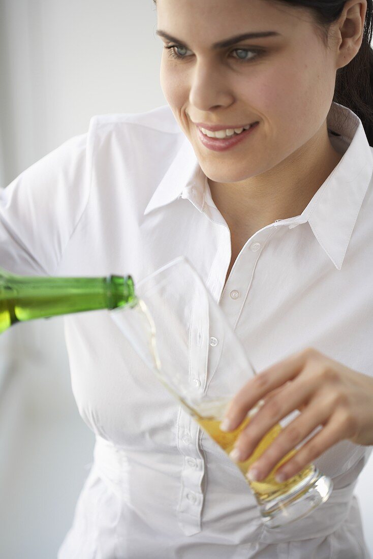 Junge Frau schenkt ein Glas Bier ein