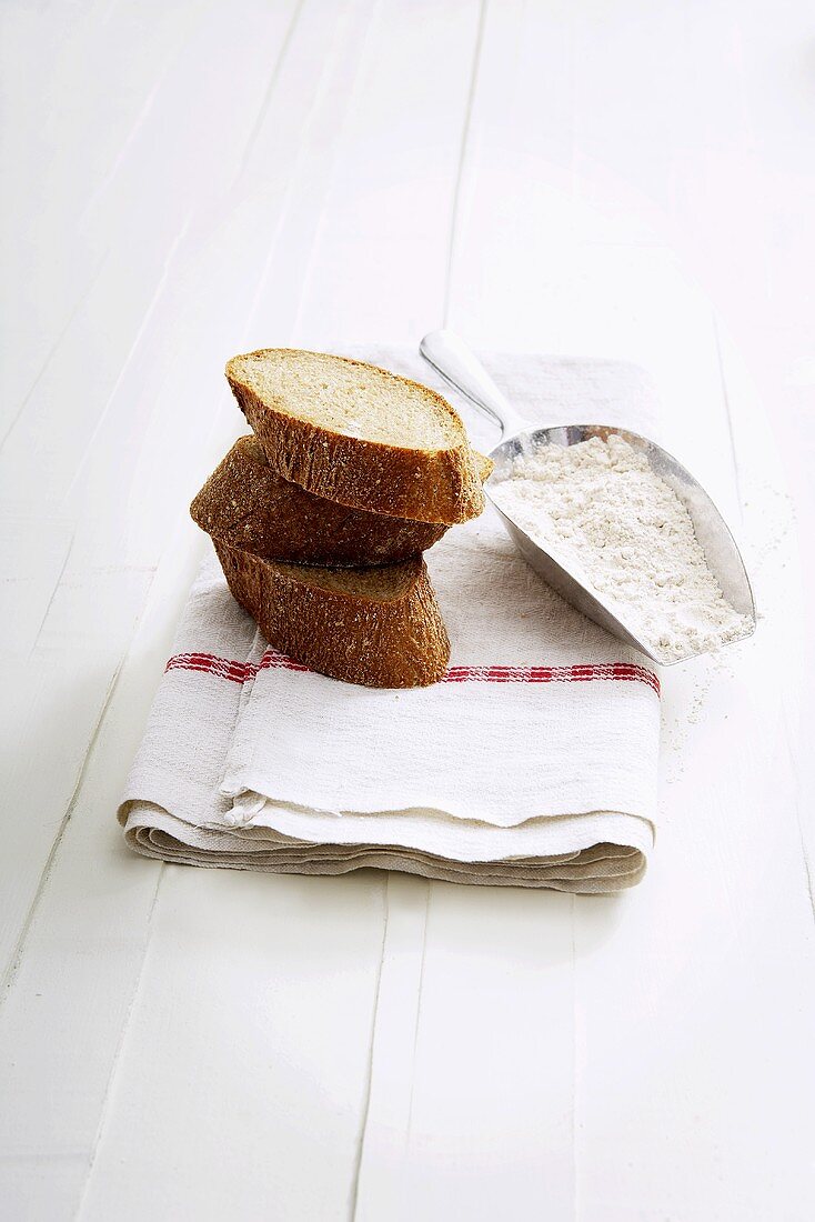 Three slices of wholemeal baguette, flour in scoop