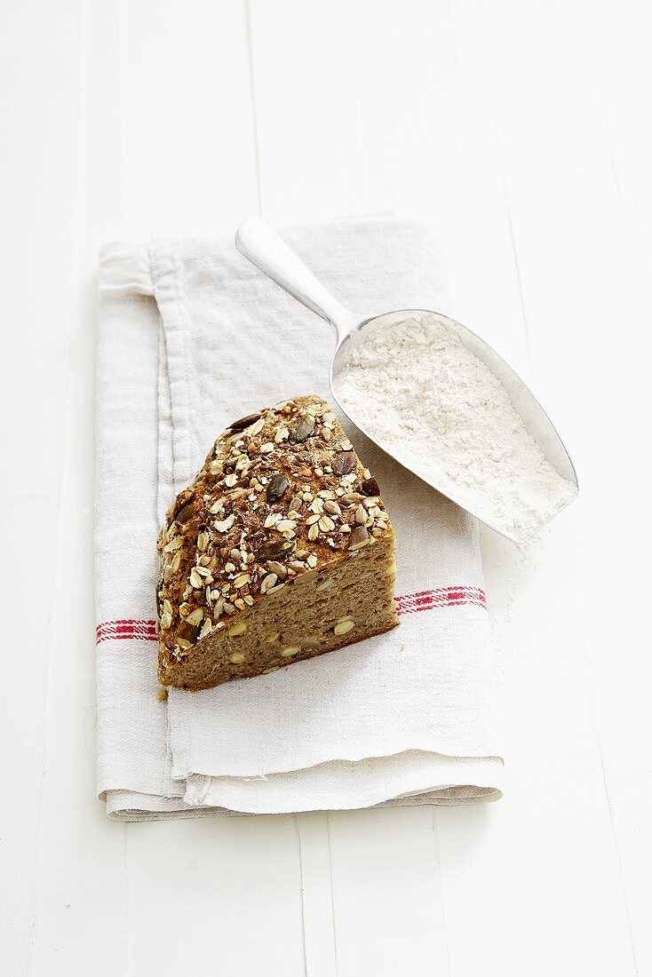 Ein Stück Körnerbrot und Schaufel mit Mehl