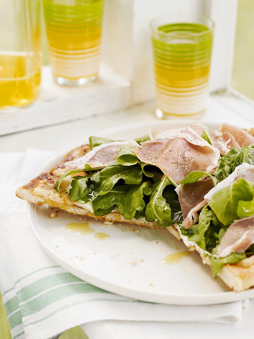 Pizza topped with salad leaves and ham
